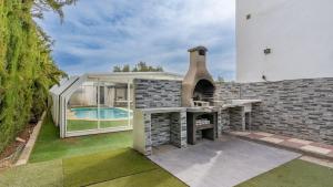 un patio trasero con horno al aire libre y piscina en Villa de los Sueños Atarfe by Ruralidays en Atarfe
