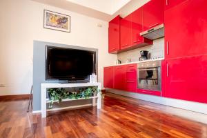 a kitchen with red cabinets and a flat screen tv at Appartamento nel cuore della città in Livorno