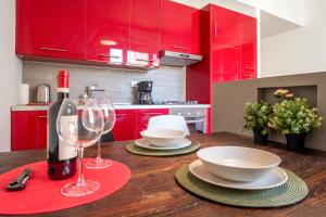 uma cozinha vermelha com uma mesa de madeira e copos de vinho em Appartamento nel cuore della città em Livorno