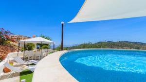 een zwembad met stoelen en een parasol bij Casa del Pino Casarabonela by Ruralidays in Casarabonela