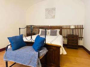 a bedroom with a bed with blue pillows and a chair at Avis Guesthouse in Évora