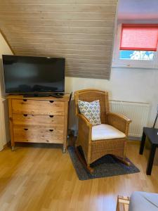 a living room with a tv and a chair and a dresser at Apartment Düsseldorf-Süd in Düsseldorf