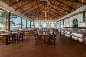 een eetkamer met tafels en stoelen en de oceaan bij Aya Sophia Villa Garden Hotel in Dar es Salaam