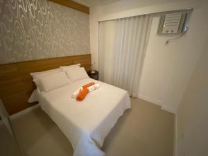 Un dormitorio con una cama blanca con una toalla naranja. en Exclusivo Quarto e Sala na Praia da Barra em Salvador - Concept House Brazil, en Salvador