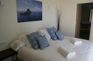 Una cama blanca con almohadas azules y blancas. en Extravagant Ibiza Villa Casa Tranquila SArgamassa 5 Bedrooms Fantastic Sea Views and Private Pool Santa Eulalia, en Santa Eulària des Riu