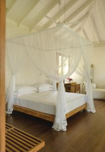 a bedroom with a canopy bed with white drapes at Kurulu Bay in Ahangama