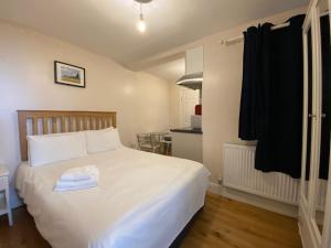 a bedroom with a white bed and a kitchen at Earl's Court Studios in London