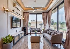 a living room with two couches and a tv at SaffronStays Nishta - 4BR pet-friendly villa with pool, turf, gazebo & terrace BBQ views in Alibaug in Alibaug