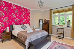 a bedroom with a bed and a pink wall at Delightful apartment in prime location near Hampstead Heath by UnderTheDoormat in London