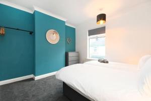 een blauwe en witte slaapkamer met een bed en een raam bij Modern Town House in Chesterfield & The Peaks in Newbold