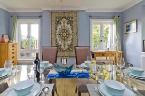 a dining room with a table and chairs and windows at Delightful apartment in prime location near Hampstead Heath by UnderTheDoormat in London