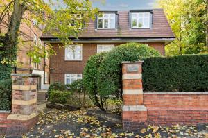 a house with a brick wall and a hedge at Delightful apartment in prime location near Hampstead Heath by UnderTheDoormat in London