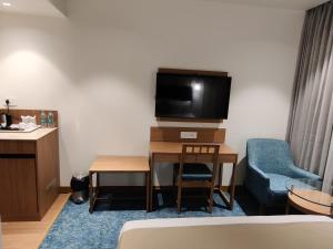 Habitación de hotel con TV y silla azul en Chryso Hotels Pvt Ltd, en Ankleshwar