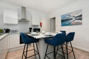 a kitchen with a table and blue chairs in a kitchen at Modern Town House in Chesterfield & The Peaks in Newbold