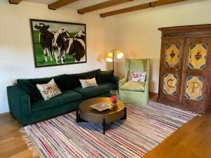 a living room with a green couch and a table at Das Schusterhäusl - Urlaub im oberbayerischen Baudenkmal in Samerberg