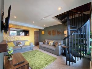 a living room with two couches and a staircase at Luxury tree-house with optional ESPA Spa in Canterbury