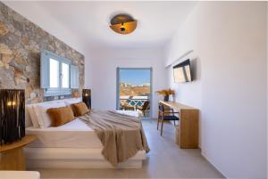 a bedroom with a bed and a desk and a window at Infinity Blue Suites & Spa in Astypalaia Town