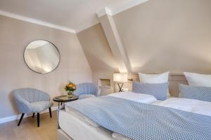 a bedroom with a bed and two chairs and a mirror at Hotel Eisenhut in Rothenburg ob der Tauber