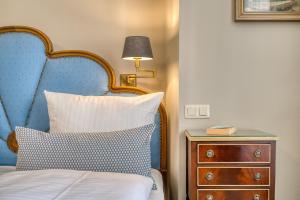 a bed with a blue headboard next to a night stand at Hotel Eisenhut in Rothenburg ob der Tauber