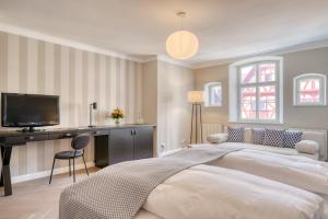 a bedroom with two beds and a desk and a television at Hotel Eisenhut in Rothenburg ob der Tauber