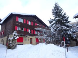 een gebouw met rode luiken in de sneeuw bij Las aclas in Valbella