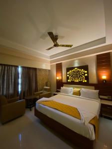 una habitación de hotel con una cama grande y una silla en Maya Residency, en Tiruchchirāppalli
