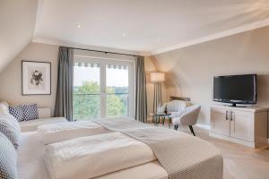 a white bedroom with a large bed and a television at Hotel Eisenhut in Rothenburg ob der Tauber
