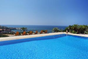 a swimming pool with chairs and the ocean in the background at Seafront 5 Bedroom Villa Paradise in Sea Caves in Peyia