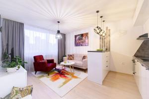 een woonkamer met een rode stoel en een bank bij Apartment UNA Alipasino with two bedrooms in Sarajevo