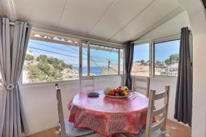 una mesa con un bol de fruta en una habitación con ventanas en NOUVEAU Cabanon Calanque de Niolon vue mer et port en Le Rove