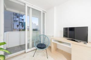 een woonkamer met een televisie en een blauwe stoel bij Apartment UNA Alipasino with two bedrooms in Sarajevo