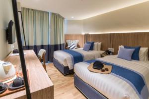 a hotel room with two beds and a television at Bella B Hotel in Nonthaburi