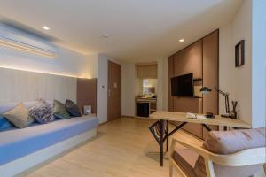 Habitación con cama, escritorio y TV. en Bella B Hotel, en Nonthaburi