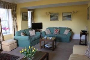 uma sala de estar com dois sofás azuis e uma televisão em St Marys Farmhouse - Traditional Country Farmhouse with Open Fire em Fochabers