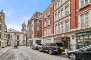 una calle de la ciudad con coches estacionados frente a los edificios en 2-Bed 2-Bathroom Mayfair - Maddox St en Londres