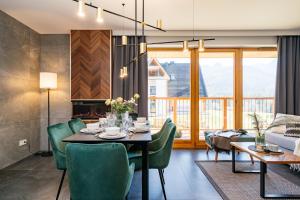 a dining room with a table and green chairs at Polana Resort by LoftAffair in Kościelisko