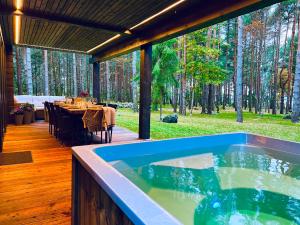 a jacuzzi tub on a deck with a dining table at Jõiste Beach Villa in Jõiste