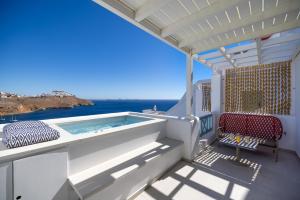 a balcony with a hot tub and a chair at Infinity Blue Suites & Spa in Astypalaia Town