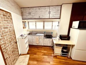 a small kitchen with a white refrigerator and a sink at Ukishima bldg in Makishimachi