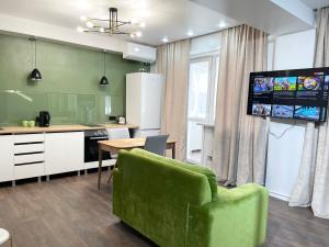 ein Wohnzimmer mit einem grünen Sofa und einer Küche in der Unterkunft Apartment on KShT in Öskemen