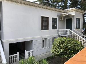 a white house with a porch and a staircase at House 122 in K'obulet'i