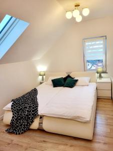 una camera da letto con un grande letto bianco con cuscini verdi di APART KARKONOSZE - Klimatyzowany Apartament Charlotte Karpacz na deptaku z parkingiem w cenie a Karpacz