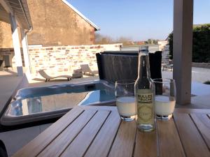 Una botella de vino y dos copas en una mesa de madera. en Les chambres d'à côté en Roye