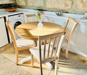 uma mesa de madeira com duas cadeiras e um vaso com flores em Otley Cottage em Otley