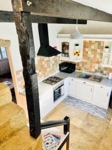 a kitchen with white cabinets and a stove top oven at Otley Cottage in Otley