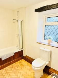 a bathroom with a toilet and a bath tub at Otley Cottage in Otley