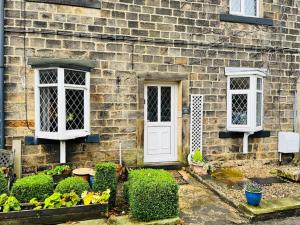 a brick house with a white door and two windows at Otley Cottage in Otley