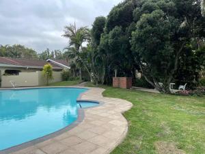 a swimming pool in a yard next to a house at Sea Casa in Scottburgh