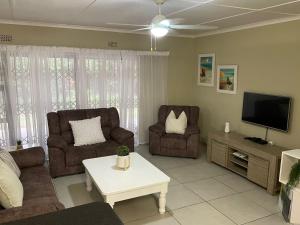 a living room with two couches and a flat screen tv at Sea Casa in Scottburgh