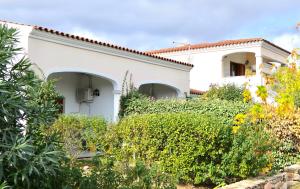 een wit huis met struiken ervoor bij Graziosi appartamenti a Budoni con aria condizionata a soli 300 mt dal mare in Budoni